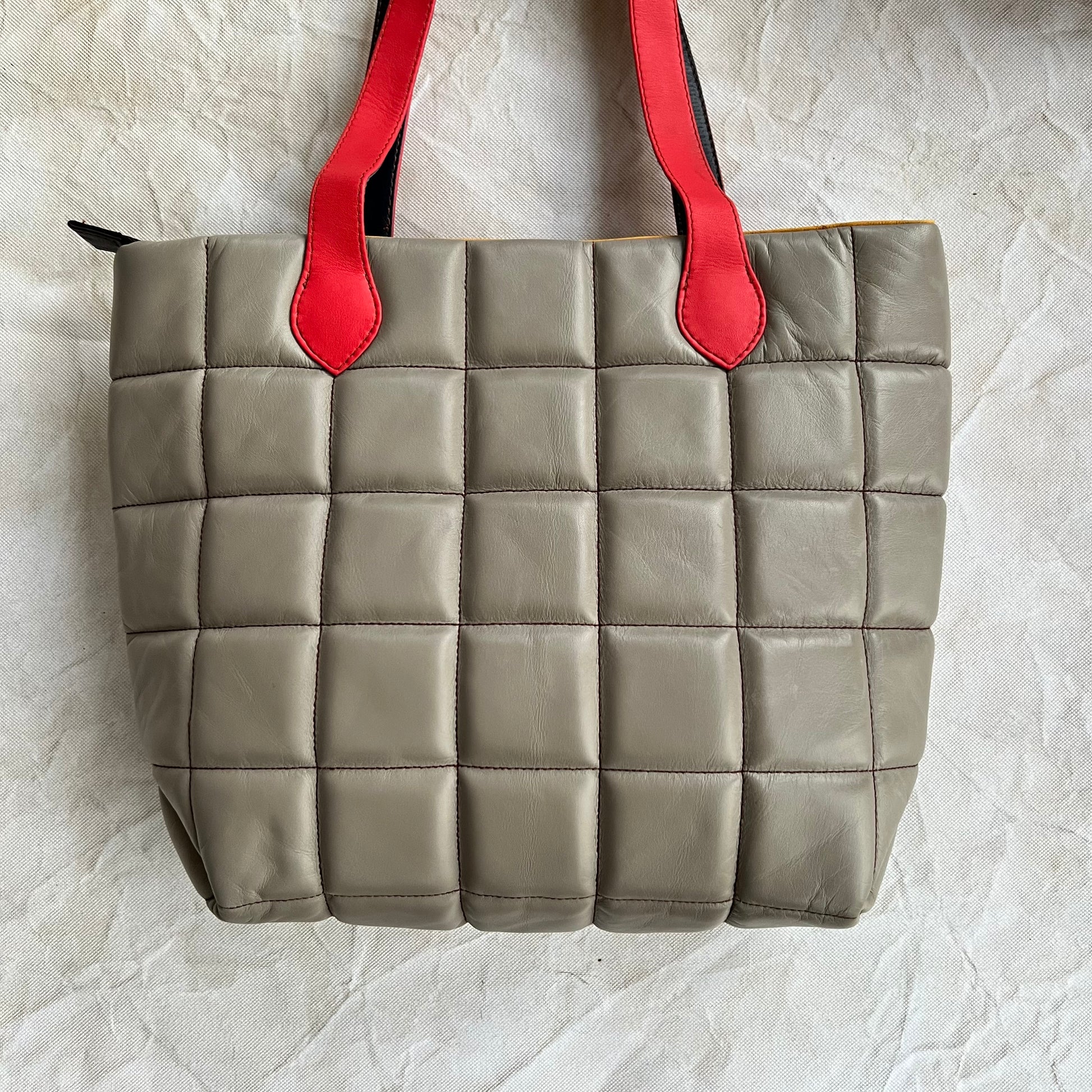 back view of taupe tote with red handles.