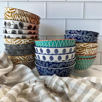 3 stacks of assorted bowls on a countertop with a dishtowel.