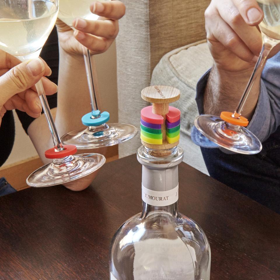 rainbow wine rings and stopper displayed on a wine bottle surrounded by people drinking wine