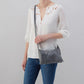 a woman wearing the gray whipstitch paulette small crossbody against a light gray background