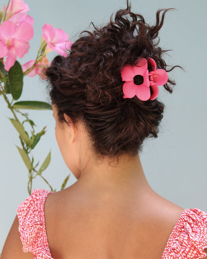 back of person's head wearing pink flower claw clip in an up-do.