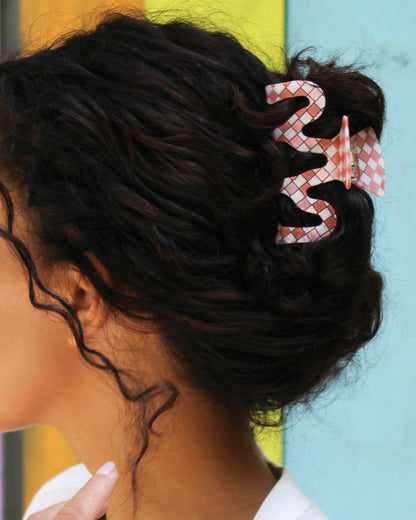 side view of person's head with pink checked claw clip on a messy bun.