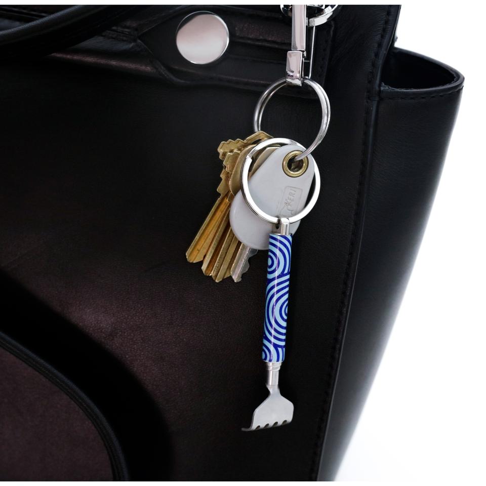 mini backscratcher displayed on a keychain hanging on a black purse on a white background