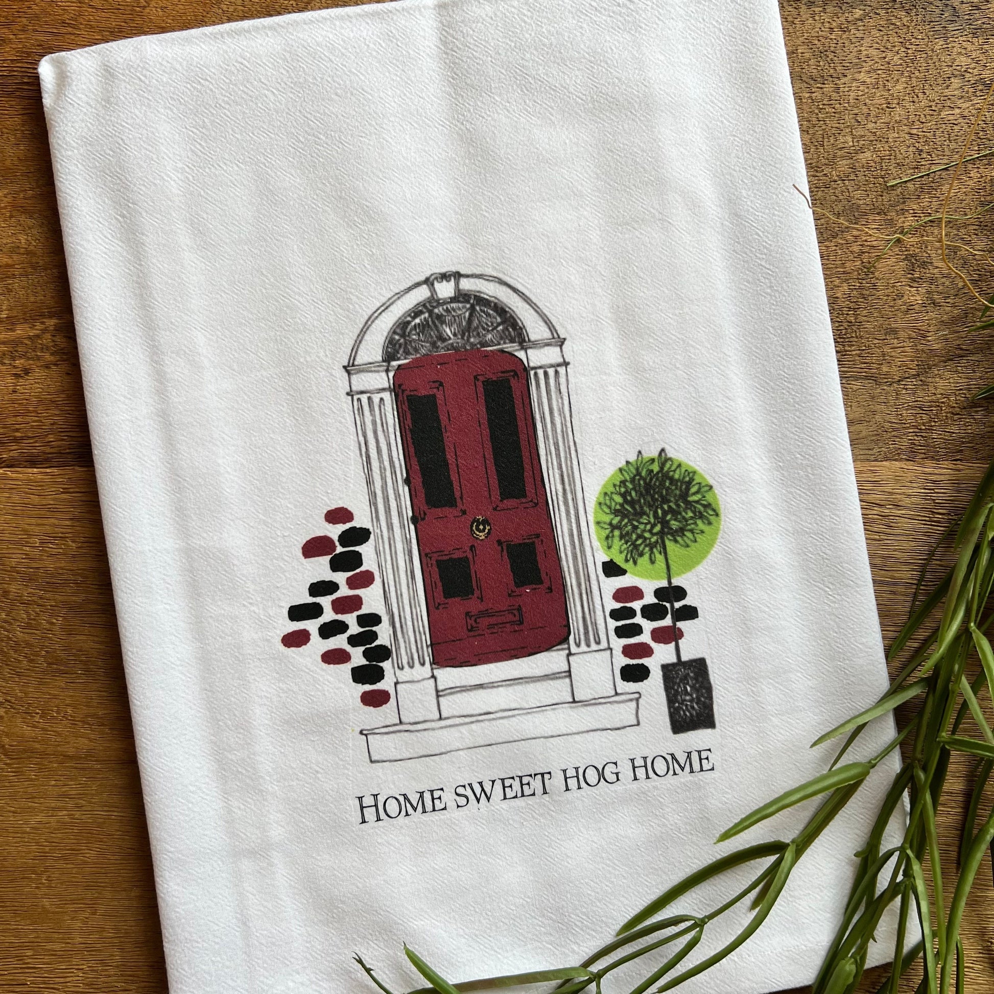 white towel with front door design and text "home sweet hog home" along the bottom.