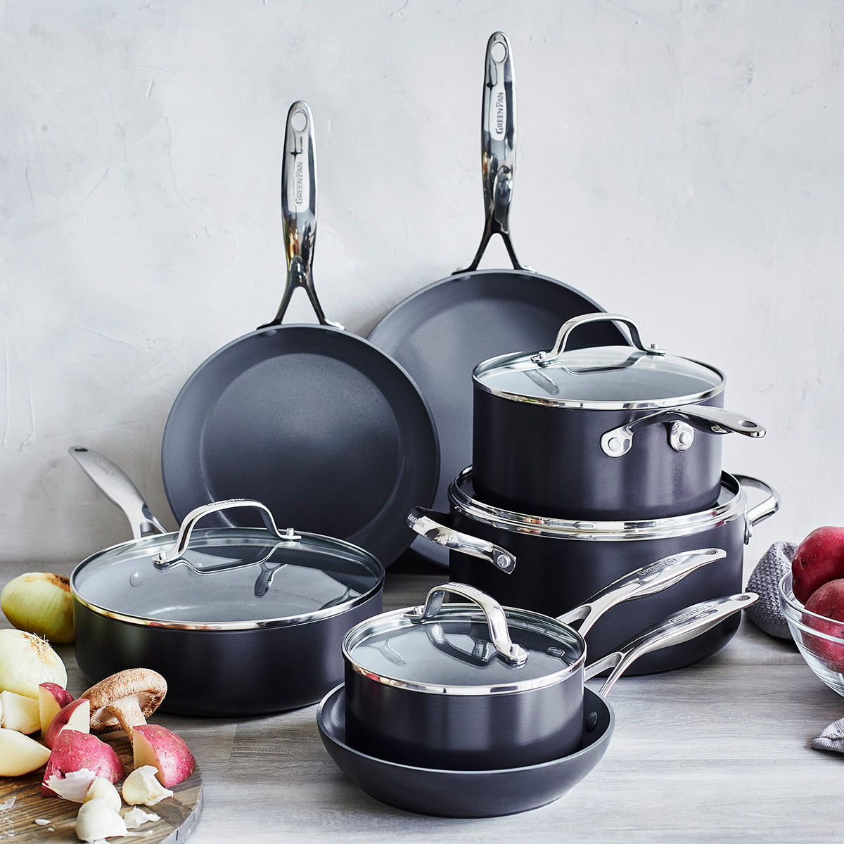 cookware arranged on wooden countertop with light grey background.