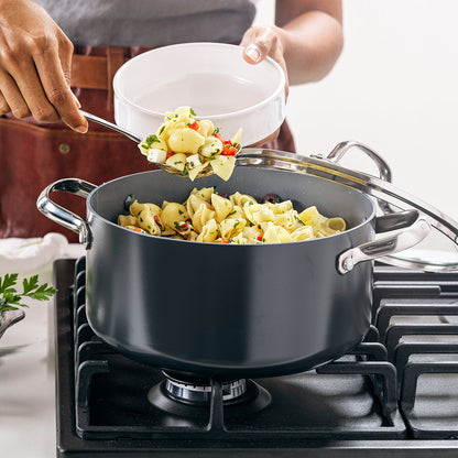 a person scooping a cooked pasta meal out of the valencia pro nonstick stockpot from the stovetop