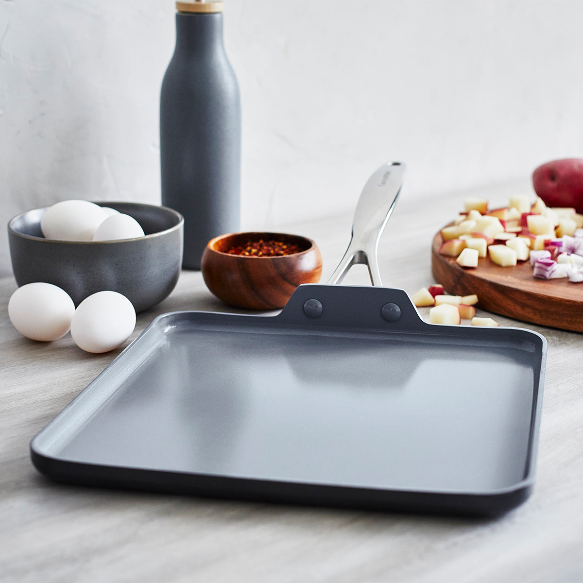 Nonstick Square Griddle set on a countertop surrounded by eggs, potatoes and spices