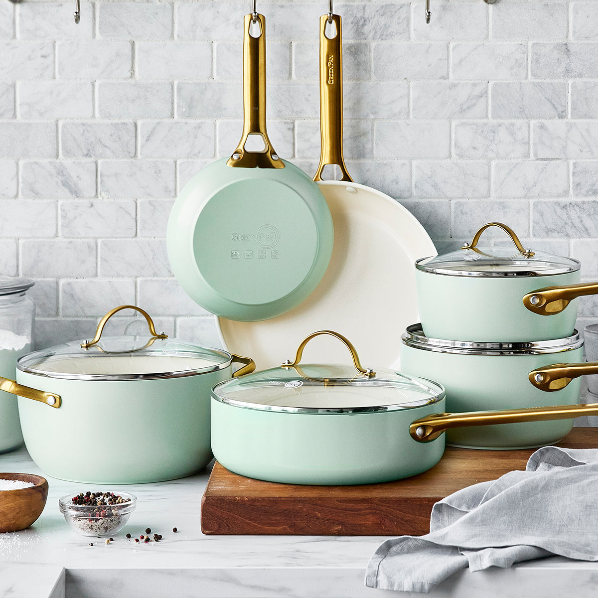 mint green cookware arranged on marble countertop with grey tile backsplash.