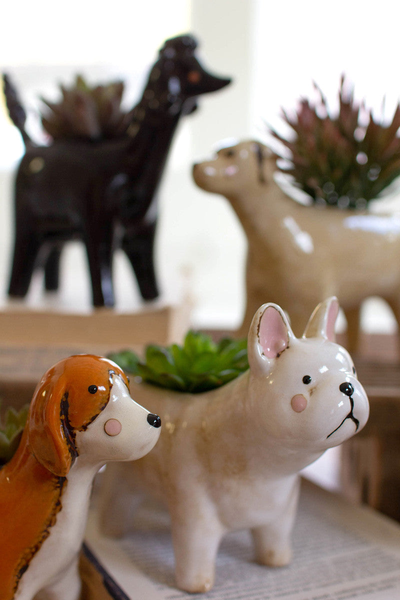 close up view of pug and beagle ceramic dog planters sitting on stacked books with two other ceramic dog planters in the background