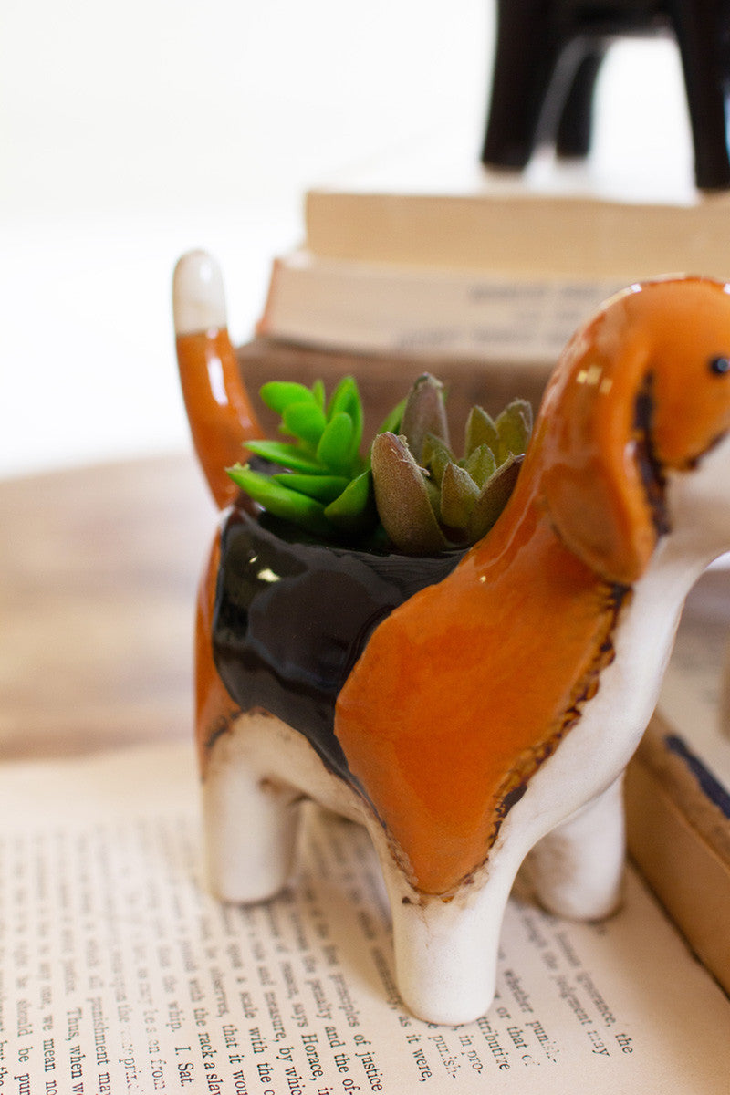 close up view of the beagle ceramic dog planter sitting on stacked books against a white background