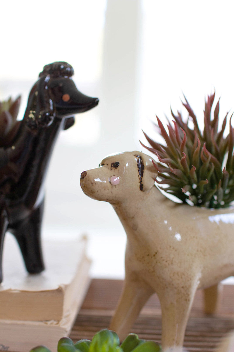 close up view of the labrador and poodle ceramic dog planters displayed on stacked books against a white background