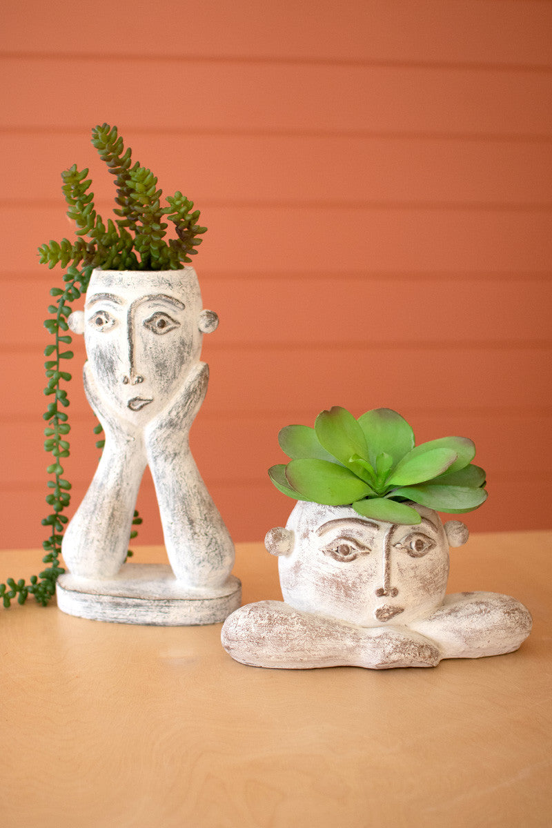 short and tall ceramic face planters filled with succulents and displayed on a copper painted slat wall