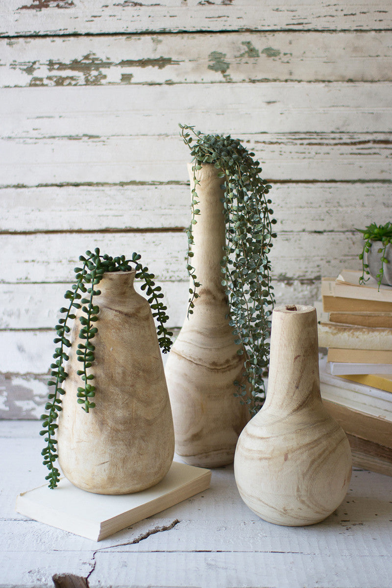 all three sizes of carved wooden vases filled with hanging succulents with stacked books against a whitewashed wood background
