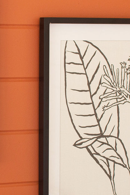 close up view of the framed black leaf print against an orange shiplap wall
