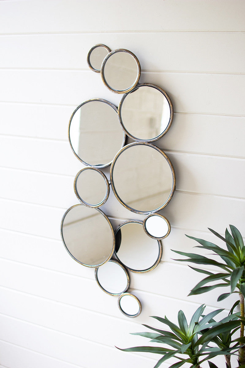 multiple sizes of round mirrors strung together and displayed on a white wood slat wall