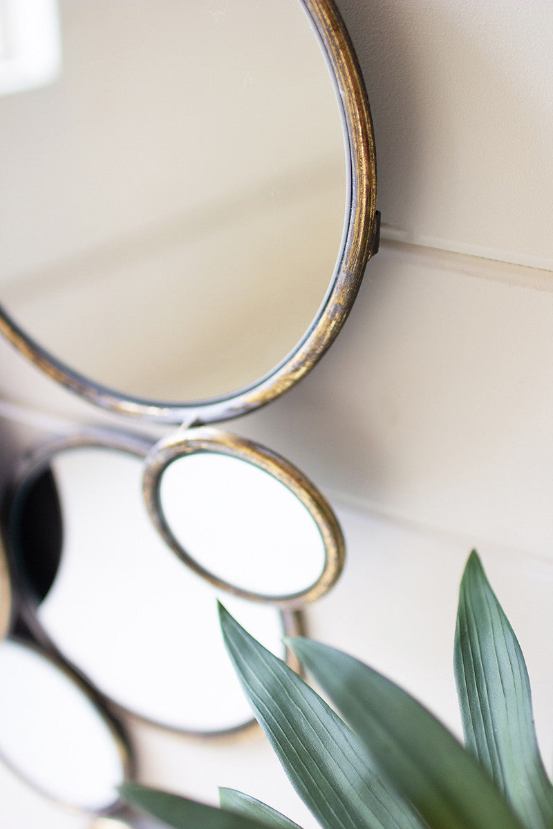 close up view of the metal bubble mirrors displayed on a white wood slat wall next to a plant 