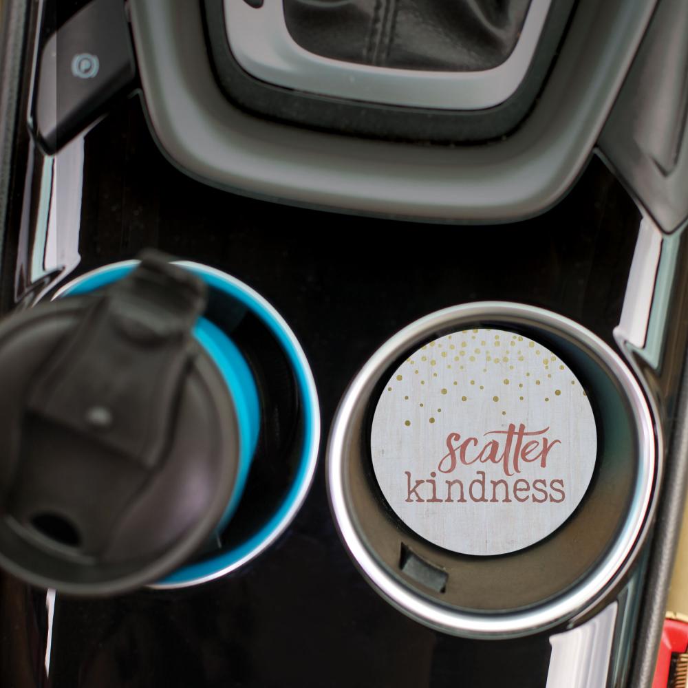 top view of the scatter kindness car coaster displayed in the cup holder in a car