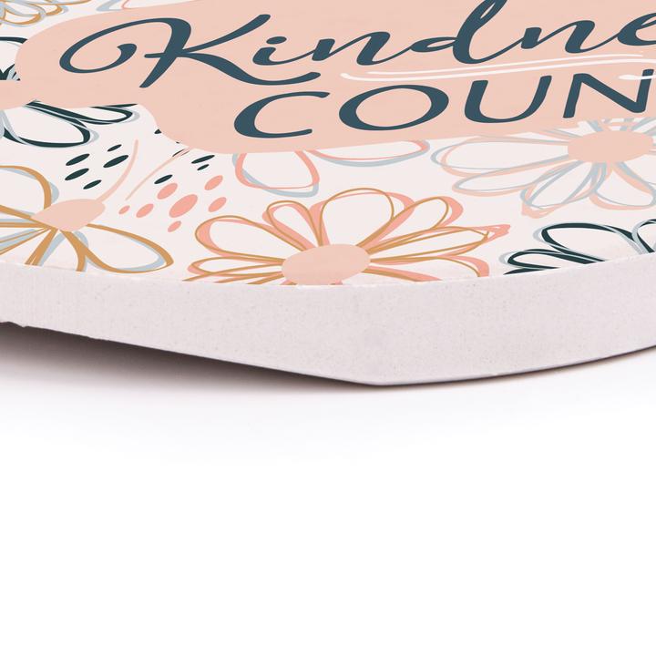 close up angled view of the kindness counts car coaster on a white surface
