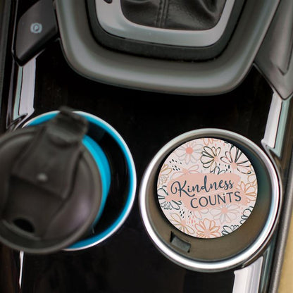 top view of the kindness counts car coaster displayed in the cup holder in a car
