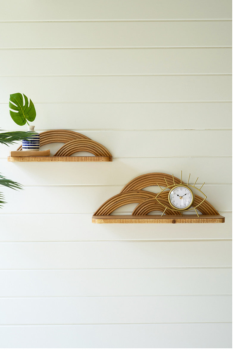 arched wooden wall shelves displayed with a gold eye clock and potted plant against a white shiplap wall