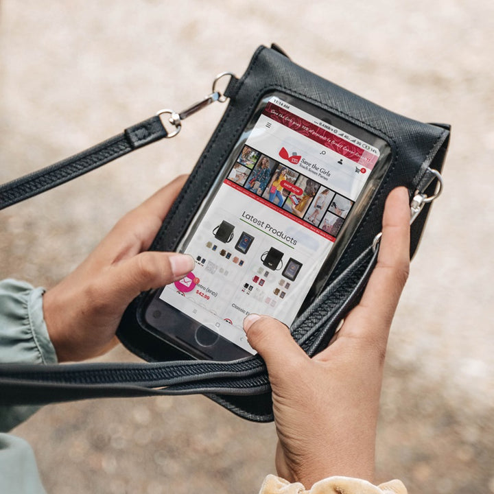 back view of a womans hands looking at her phone through the clear screen of the black just for fun cat purse