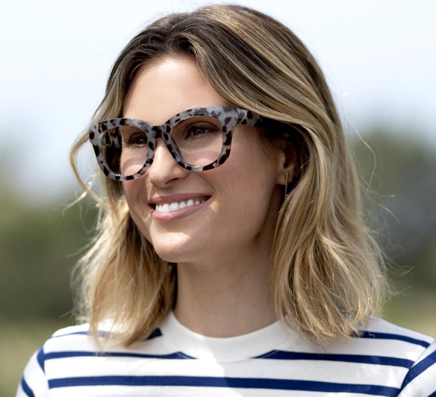angled view of a woman standing outside wearing the gray tortoise center stage glasses