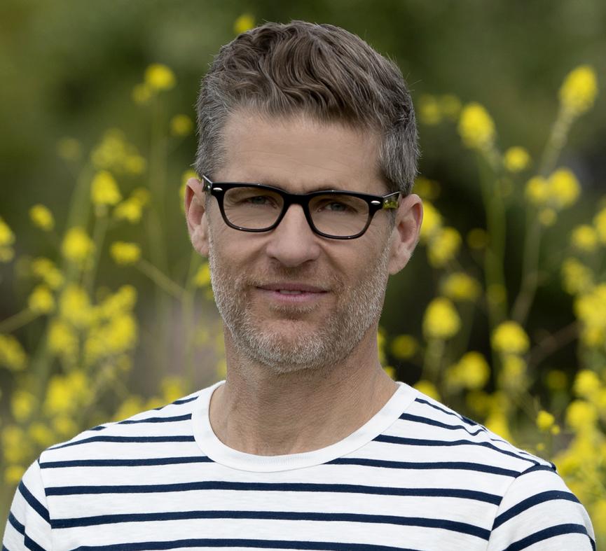 front view of a man standing in a field wearing black clark glasses