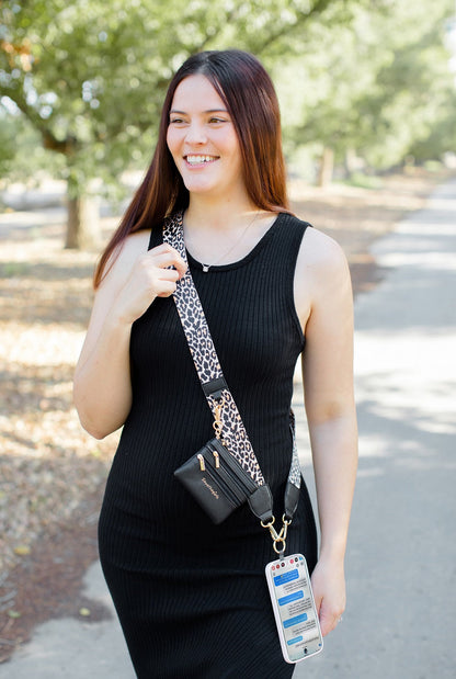 a woman walking on a path wearing the leopard clip and go strap with her purse attached