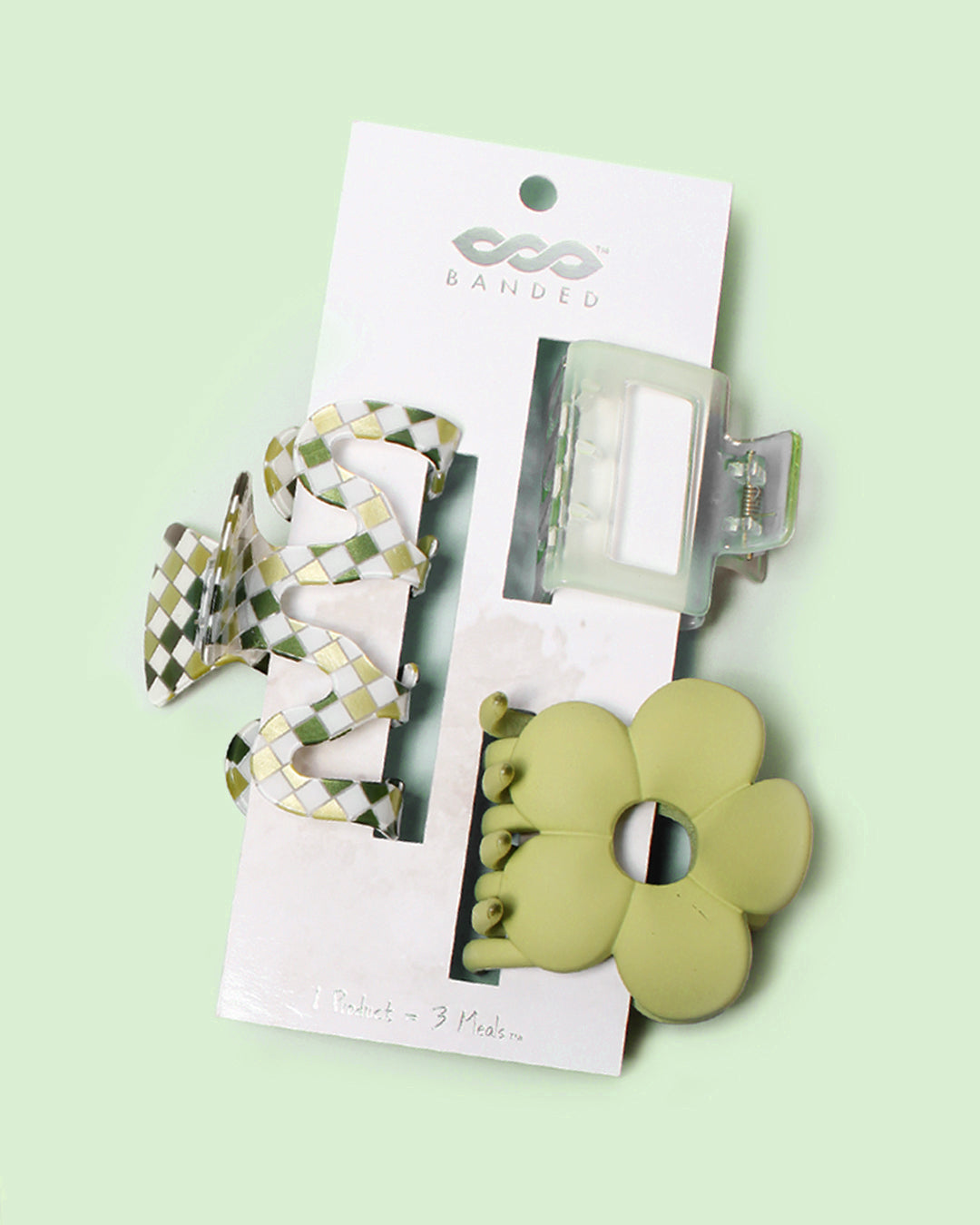 set of three green and clear claw clips displayed on a white hanging card against a light green background