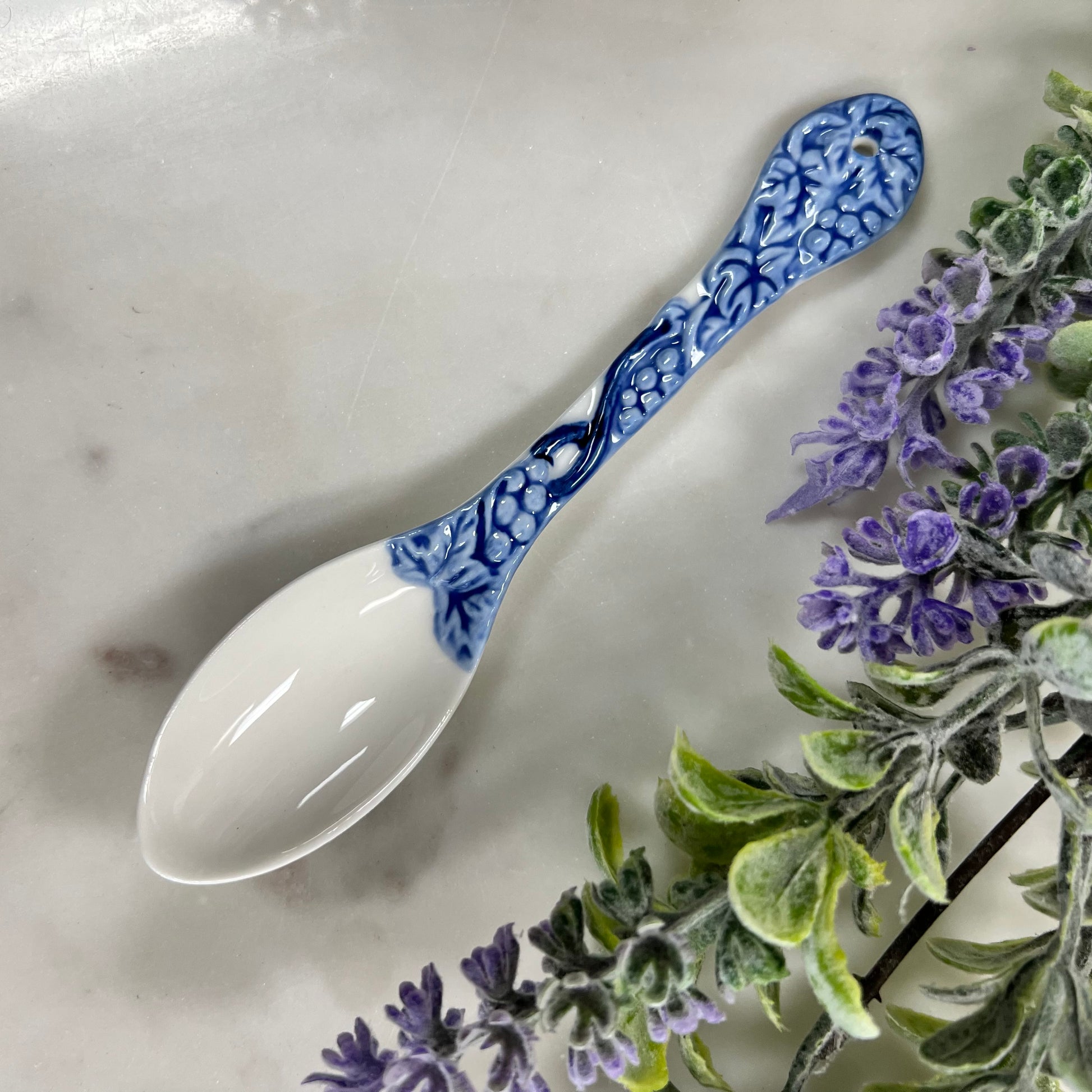 blue and white spoon with grape design on handle.