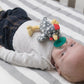 a baby laying in a crib on stiped sheets while suckling the rocky chicken pacifier