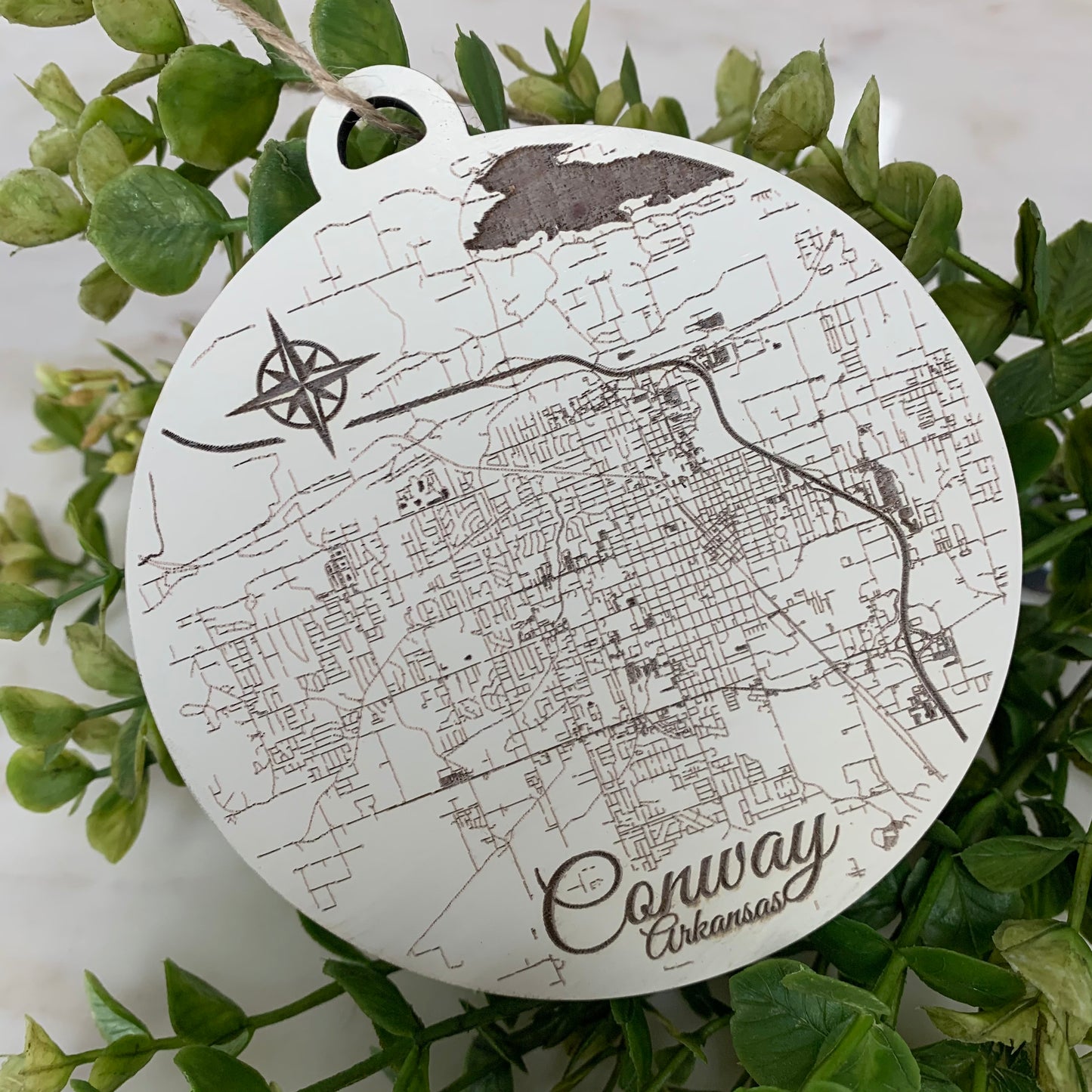 the burnt wood map ornament of conway displayed with greenery on a white background