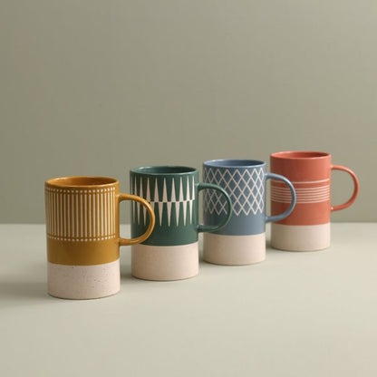 4 mugs with assorted colors and patterns on a table.