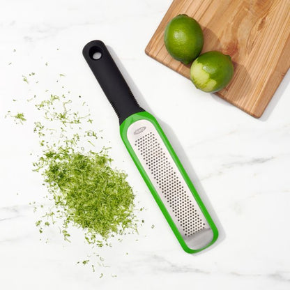zester, lime zest, and board with limes on it on marble countertop.