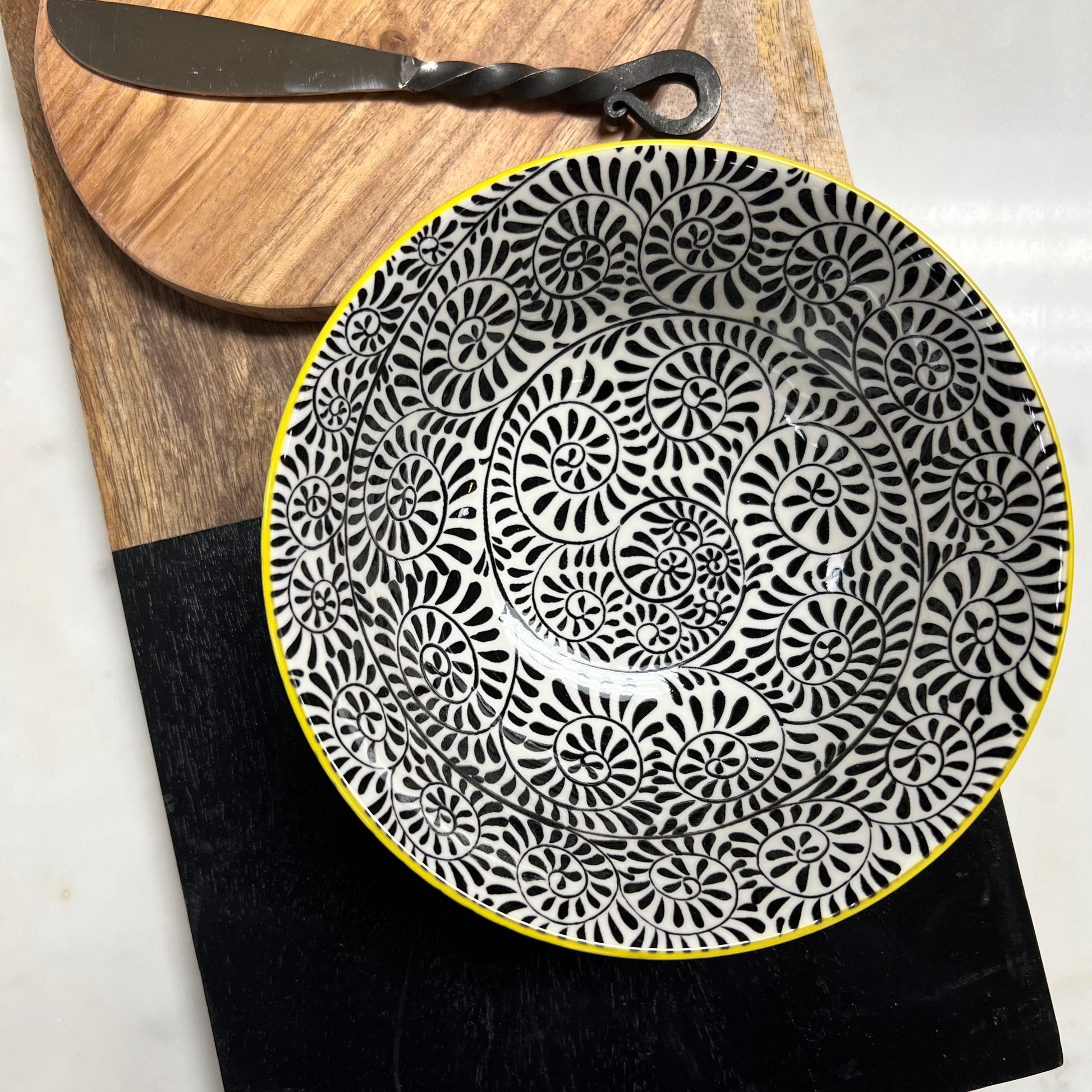 top view of black and white bowl on wood boards with spreader.