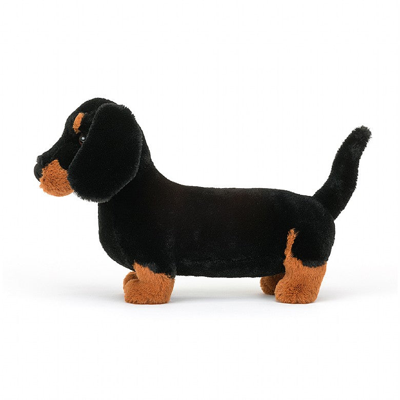 side view of freddie sausage dog plush toy is tan and black displayed against a white background