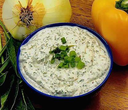 fiesta spinach dip displayed in a blue bowl next to onions and peppers on a wooden surface