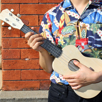 a person using the assembled ukulele against a brick wall