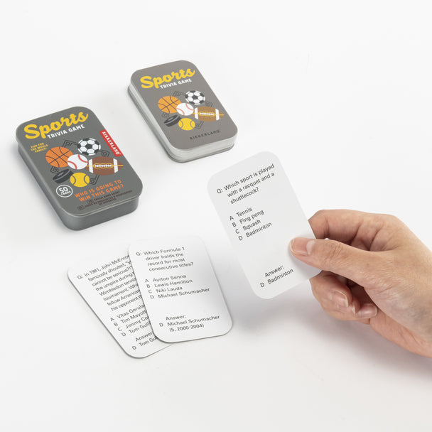 a persons hand holding a trivia card next to the protective tin against a white background