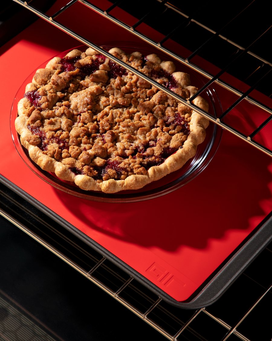 illustration of the platinum grade silicone baking mat being used on a baking sheet in an oven with a pie being baked on it