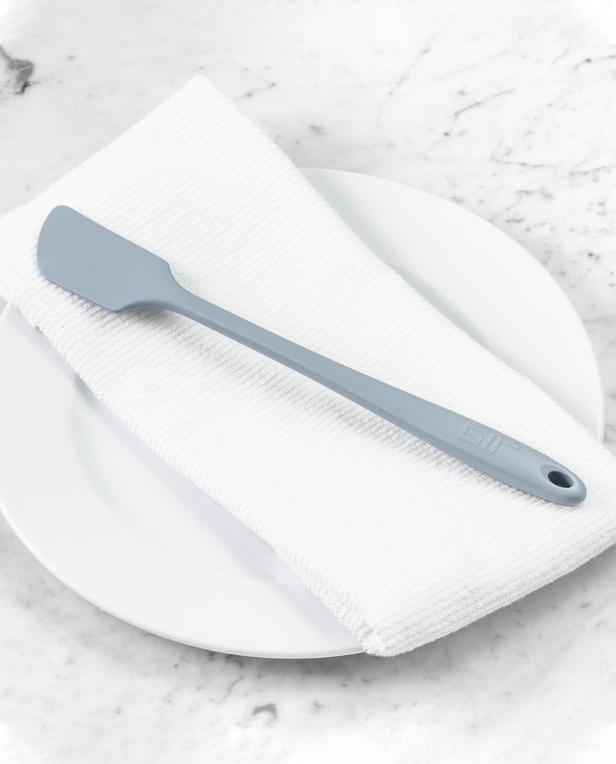 the skinny spatula displayed on a white towel placed on a white plate sitting on a white marble countertop