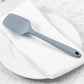the ultimate spoonula displayed on a white towel placed on a white plate sitting on a white marble countertop