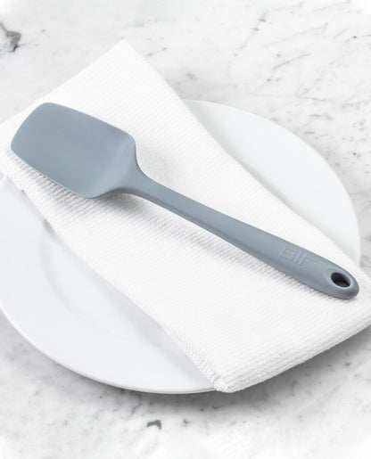the ultimate spoonula displayed on a white towel placed on a white plate sitting on a white marble countertop