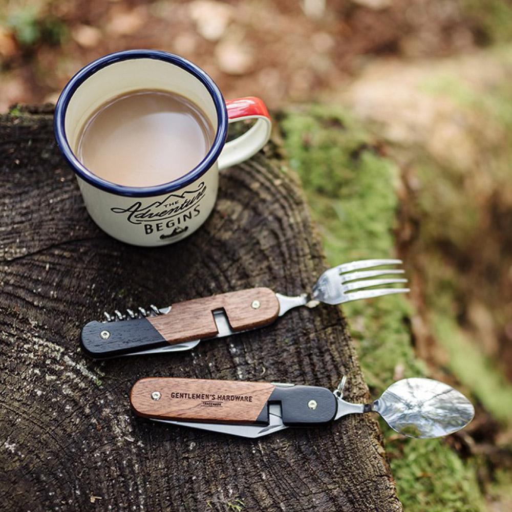 the camping cutlery tool displayed on a stump beside a mug of coffee