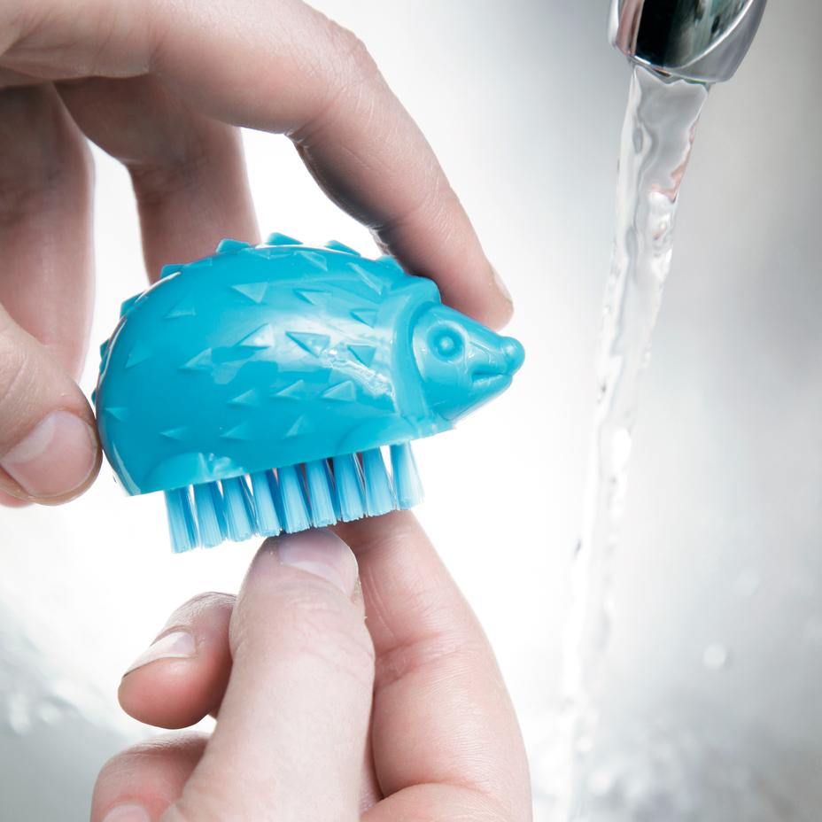 illustration of a person using the hedgehog nail brush in a sink with running water