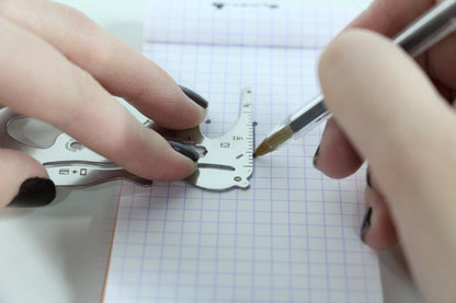 hands using PocketMonkey tool to measure and draw straight line on graph paper.