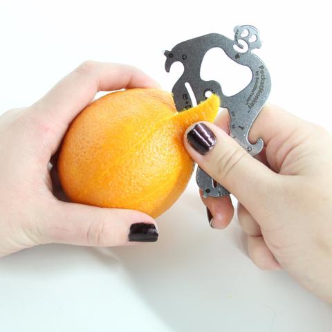 hands using PocketMonkey tool to peel an orange.