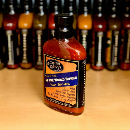  bottle of Captain Rodney's As the World Burns hot sauce on a table with a row of more bottles behind it.