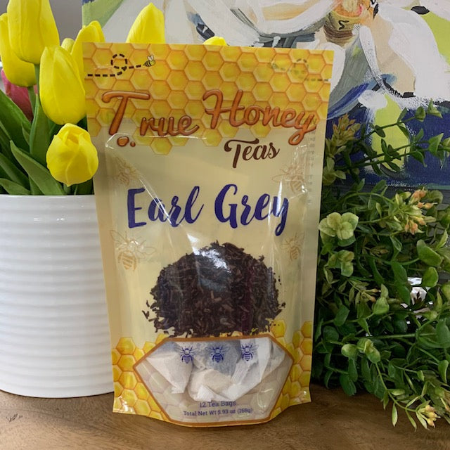 bag of earl grey tea bags surrounded by greenery and flowers.