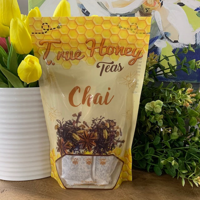 bag of chai tea bags surrounded by greenery and flowers.